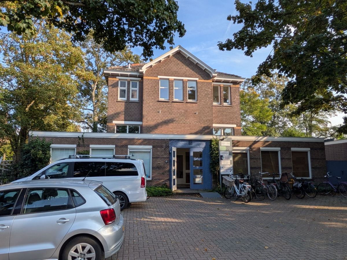 Het oude parochiehuis aan de Paulus Borstraat 37, met de blauwe entree en parkeerruimte op eigen terrein